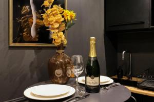 una mesa con una botella de vino y un jarrón con flores en BlackLove room, en La Ciotat 31 fotos más