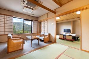 a room with a living room with chairs and a tv at KAMENOI HOTEL Tazawako in Senboku