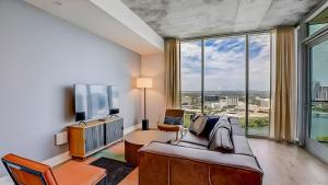 a living room with a couch and a tv at The Emma Penthouse: Modern 2BR Condo Steps from Rainey St. Lady Bird Lake in Austin