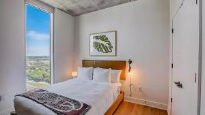 a bedroom with a bed and a large window at The Emma Penthouse: Modern 2BR Condo Steps from Rainey St. Lady Bird Lake in Austin +26 photos