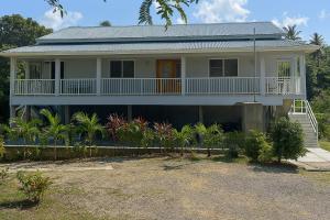a white house with a porch and a balcony at La Retraite Apt in Rodney Bay Village
