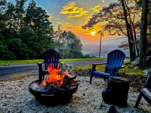 two chairs sitting next to a fire pit with the sunset at Iconic Chalet with Sauna, Hot Tub, Fire Pit, Plunge in Harpers Ferry