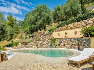 a swimming pool in a garden with a stone wall at Elegant Villa With Pool Near Diano Marina in Diano San Pietro