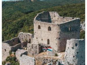 an old castle with a flag on top of it at Apartment and Room Mare Vrlika - Double Bedroom with Terrace and External Kitchenette in Maovice