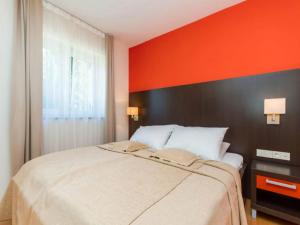 a bedroom with a large bed with an orange wall at Marina Portoro Family Friendly Apartment 3 - Two Bedroom Apartment in Lucija
