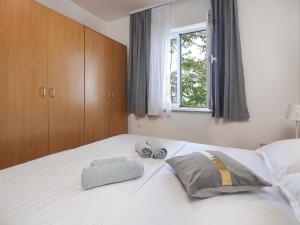 una camera da letto con un grande letto bianco con una finestra di Peaceful Nature Retreat Near Krk Town with BBQ and Parking - Standard Two Bedroom Apartment a Vrh