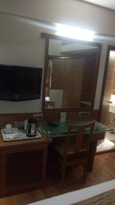 Habitación con escritorio, espejo y silla. en The Royal Orchid Hotel, Chembur en Bombay