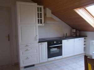 a kitchen with white cabinets and a stove at Guesthouse König in Gommersheim