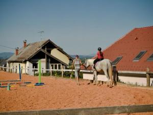 Twee mensen te paard voor een gebouw. bij Standard One Bedroom Apartment in Čatež ob Savi