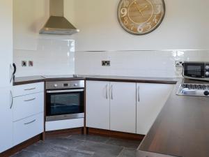 a kitchen with white cabinets and a clock on the wall at The Greenkeeper - Uk39823 in Portpatrick +13 photos