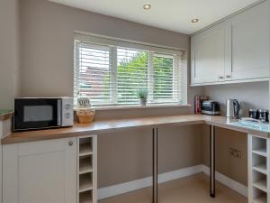 a kitchen with a counter with a microwave and a window at Lamsey Cottage in Heacham