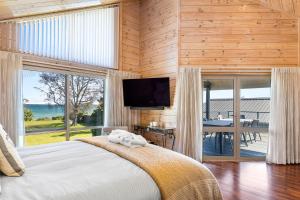 a bedroom with a bed and a television and a table at Still Water Retreat - beautiful lake front location and living in Waitahanui