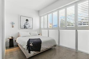 1 dormitorio con 1 cama con paredes y ventanas blancas en C & C by the Sea Studio, en Coolum Beach