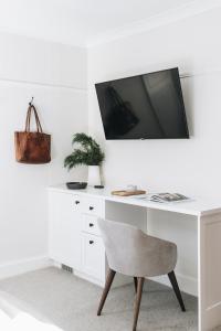a white desk with a tv and a chair at Dormie House in Moss Vale