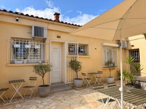 une terrasse avec des chaises et un parasol en face d'une maison dans l'établissement Chambre simple avec terrasse privée - Proche tram et centre - Cuisine et Salle de bain en partage, à Montpellier
