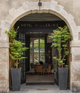 un arco che conduce alla hall di un hotel con alberi in vaso di Millésime Hôtel a Parigi