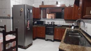 a kitchen with stainless steel appliances and wooden cabinets at COP30 house in Ananindeua