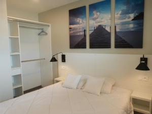 a bedroom with a white bed with three paintings on the wall at Appartement neuf en bord de mer pour 6 pers, balcon, piscine, jacuzzi, parking, animaux admis - FR-1-194-233 in La Tranche-sur-Mer