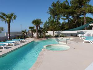 a swimming pool with chairs and palm trees at Appartement neuf en bord de mer pour 6 pers, balcon, piscine, jacuzzi, parking, animaux admis - FR-1-194-233 in La Tranche-sur-Mer +15 photos