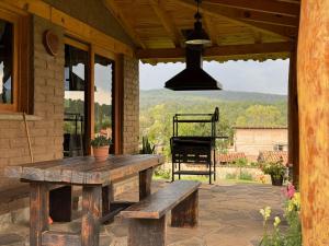 タパルパにあるCabaña Lince Tapalpaの木製のテーブルとベンチ付きのポーチ