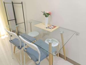 une table en verre avec des chaises et un vase avec des fleurs dessus dans l'établissement S Residences Tower 1 - near MOA & Ayala Malls Manila Bay, à Manille