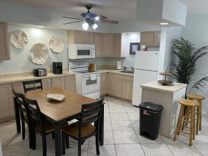 cocina con mesa, sillas y nevera blanca en Beachside 1-Bedroom Condo in Cocoa Beach, Florida - 125 Feet to Beach!, en Cocoa Beach