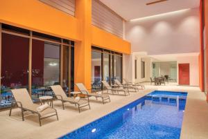 a swimming pool with chairs and a swimming poolvisor at Fiesta Inn Express Puebla Explanada in Puebla +39 photos