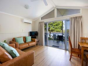 a living room with a couch and a television and a table at Reflections Brunswick Head - Holiday Park in Brunswick Heads