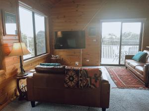 a living room with a couch and a flat screen tv at Barefoot Bungalow in Bicheno