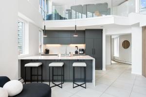 a kitchen with black cabinets and bar stools at The Vancouver Penthouse, 2-Level, Patios, Hot Tub in Vancouver
