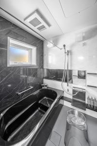 a bathroom with a bath tub and a sink at Hoshiyado Nagayama in Asahikawa