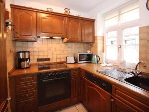 a kitchen with wooden cabinets and a sink and a microwave at Holiday home half-timbered house Bodenwerder in Kemnade