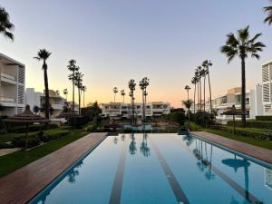 a large swimming pool with palm trees and buildings at Beachside Charming Apartment in Tamaris