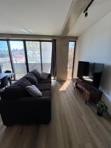 ティファナにあるComfortable condo in the heart of Tijuana 104の黒いソファと薄型テレビのあるリビングルーム