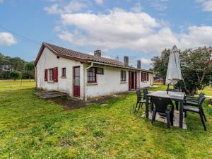 una casa con tavolo, sedie e ombrellone di Maison Landaise Spacieuse 6/7 Pers. à 500m du Lac - FR-1-521-252 a Sanguinet