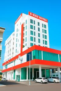 a white and red hotel with cars parked in front of it at THE REED HOTEL MELAKA formerly known as E-Red Hotel Melaka in Melaka