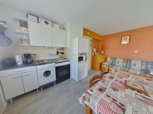 eine Küche mit weißen Schränken und einem Tisch im Zimmer in der Unterkunft Appartement cosy aux Rousses avec terrasse et proximité activités - FR-1-834-8 in Les Rousses