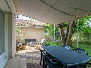 a patio with a table and chairs and a bench at Maison Charmante 3* à Mimizan: Plages, Pistes Cyclables, Jardin, Wi-Fi, pour 8 Personnes - FR-1-50-137 in Mimizan