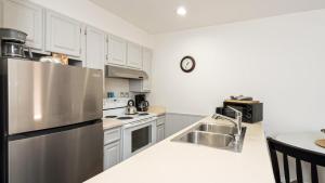 a kitchen with white cabinets and a stainless steel refrigerator at Etta Place 5 by AvantStay Ski In Ski Out Unit w Views of the Valley in Telluride