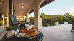 a table with a tray of bread and fruit on a balcony at De Luz by AvantStay 5 Acre Estate w Lake Pool Hot Tub in Murrieta