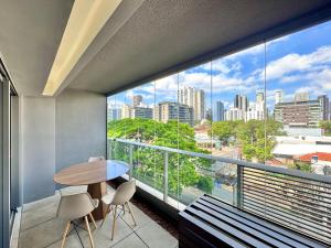 a balcony with a table and chairs and a large window at Yalla Stay - Cool Studio Habitarte in Sao Paulo