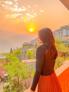 a woman standing on a balcony looking at the sunset at D Home Sapa 3 in Sa Pa