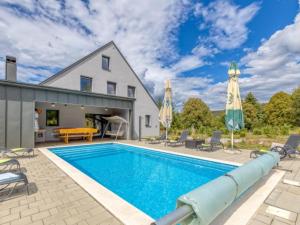 a swimming pool with chairs and umbrellas next to a house at Four Bedroom Holiday House Mali Raj with Pool in Oštarije