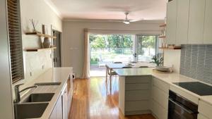 une cuisine avec des armoires blanches, un évier et une fenêtre dans l'établissement Monterra Ave Magic, à Hawks Nest