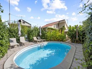 a swimming pool in a yard with chairs and a house at One-Bedroom Apartment With Pool in Brodarica