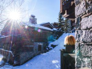 una mujer sentada en una valla en la nieve en Chalet exquis à Courchevel 1850, près des pistes, jusqu'à 10 personnes - FR-1-772-5, en Courchevel