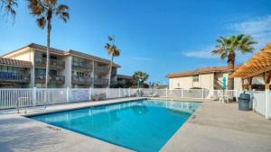 a swimming pool in front of a building with palm trees at Stay Palm by AvantStay Boardwalk Pool in Port Aransas