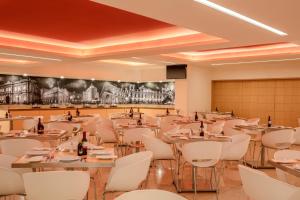 a dining room with tables and white chairs at Fiesta Inn San Luis Potosi Glorieta Juarez in San Luis Potosí