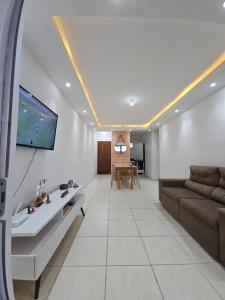 a living room with a couch and a tv on a wall at Pérola Rosa 04 in Ilhéus