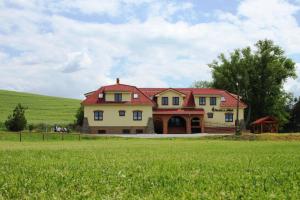 une grande maison jaune avec un toit rouge dans un champ dans l'établissement Penzion u sklepů, à Hovorany